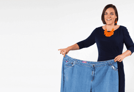 Woman posing with her old jeans after her weight loss