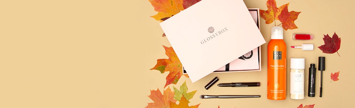 Pink GLOSSYBOX surrounded by beauty products and fall leaves