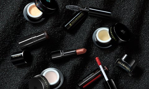Mini Beyond Veil, Mini Gel Sculpt, Mini Antimatter in Bang, Mini Hydra Veil, Mini Mascara Raven, Mini Loaded Lip Polish In Vain and Mini Precision Gel Liner on a black sand background.