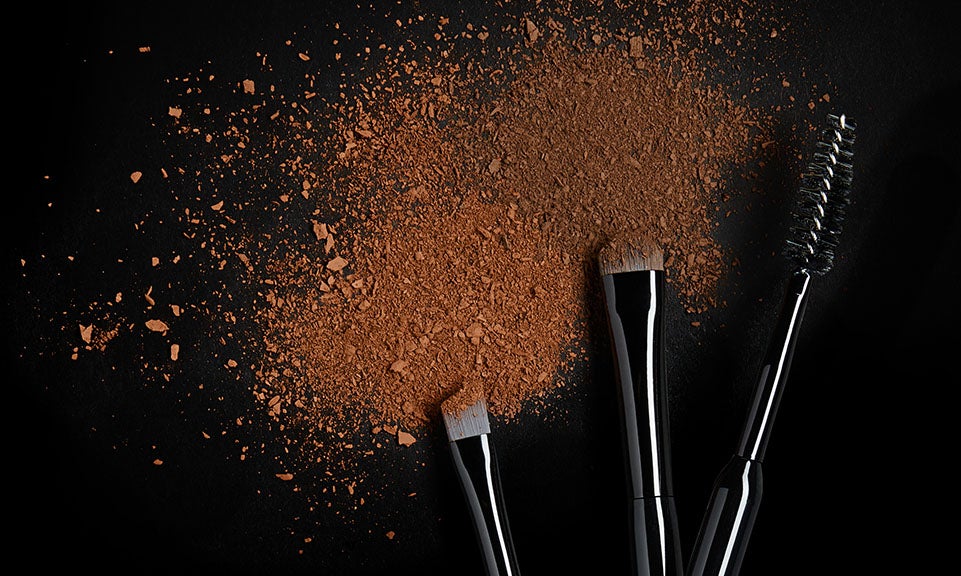 illamasqua eyebrow makeup brushes with powder brow product shattered on background