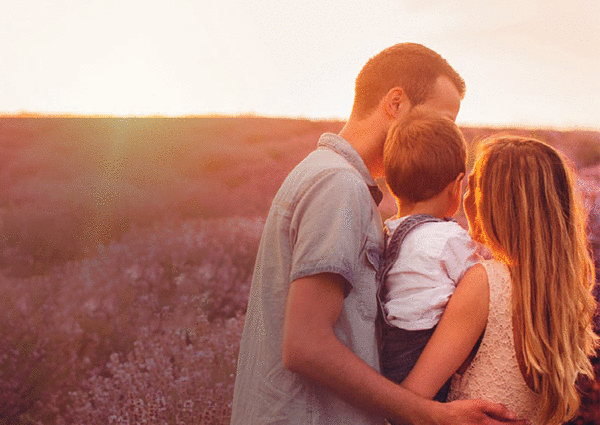Una giovane coppia con un bambino in braccio in un campo di lavanda, durante un tramonto estivo.