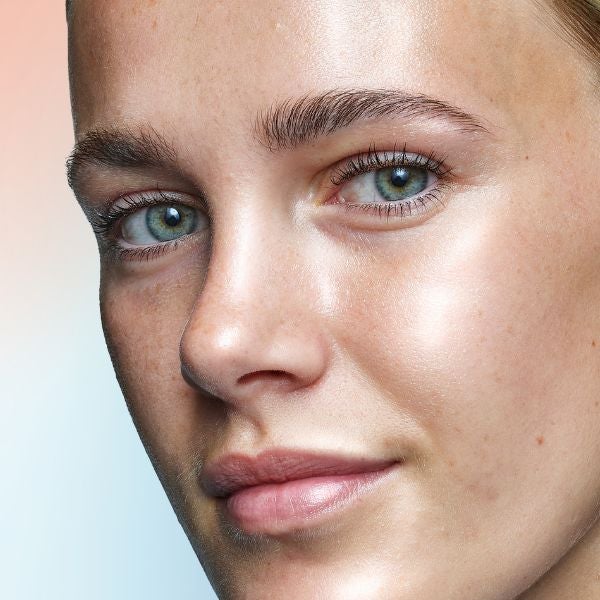 A close up shot of a woman's face smiling at the camera in front of a orange, blue and purple gradient