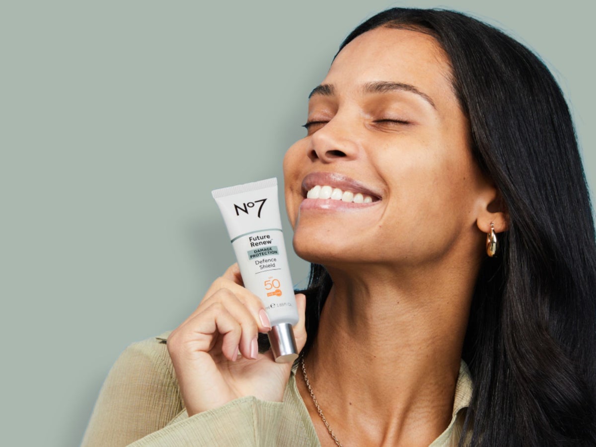 A woman applying Future Renew night serum in front of a blue background