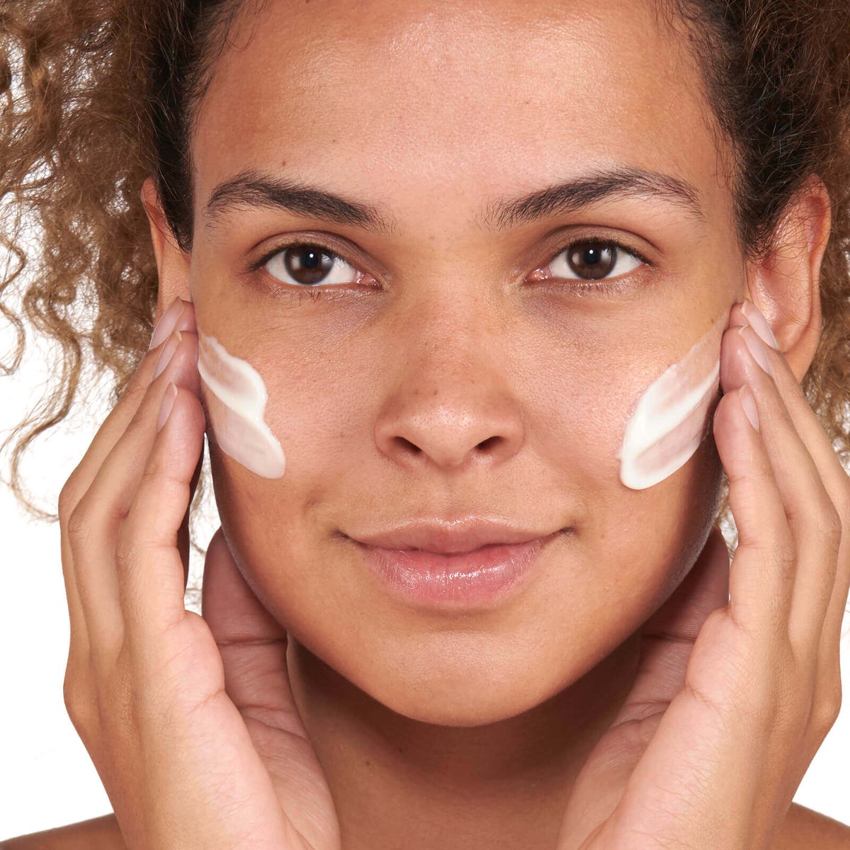 Woman applying No7 serum or moisturizer to her face