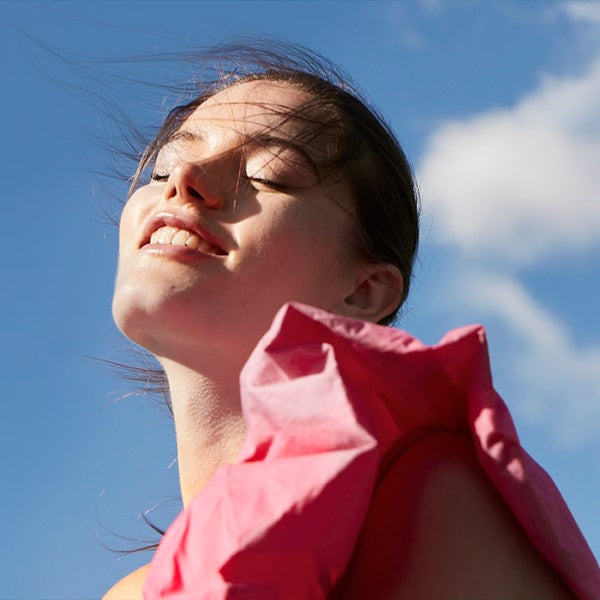 A lady enjoying the breeze of the wind with bright blue sky.