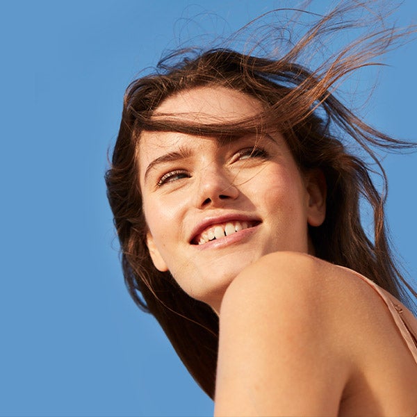 a lady smiling so bright with a blue clear sky as the background