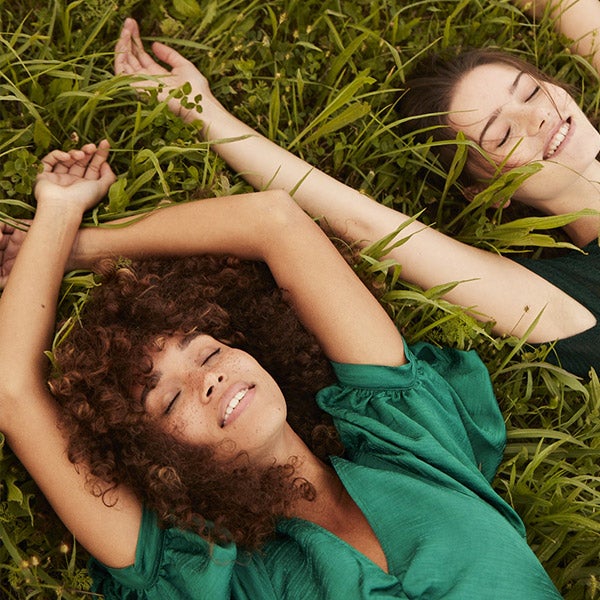 Two ladies enjoying themselves lying on the grass with breeze of fresh air.