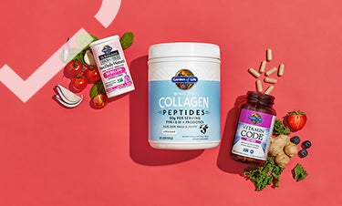 Упаковки пептидов коллагена, пробиотиков для женщин и мультивитаминов лежвт на красном полотне окруженные овощами и фруктами.