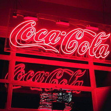 A neon Coca-Cola sign lit up with red lights