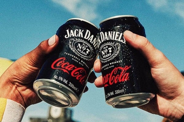 Two friends cheers two cans of Coca-Cola Jack Daniels A legend born to be tasted