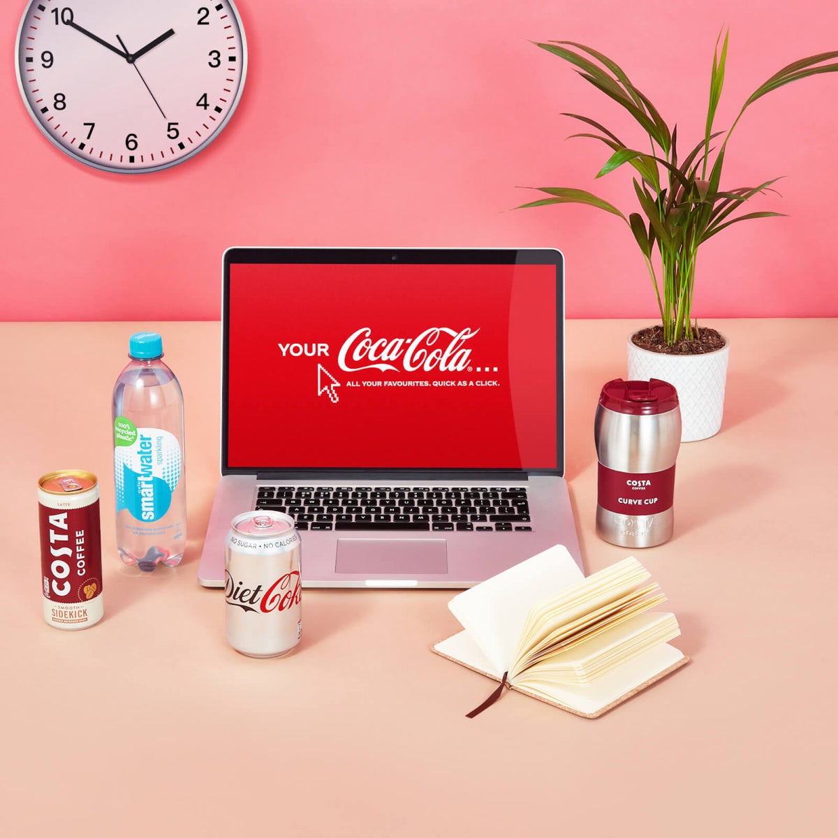 An open laptop with the Your Coca Cola logo on the screen and different Coca Cola drinks around it