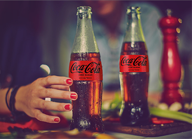 An image of a woman's hand reaching for a Coca-Cola