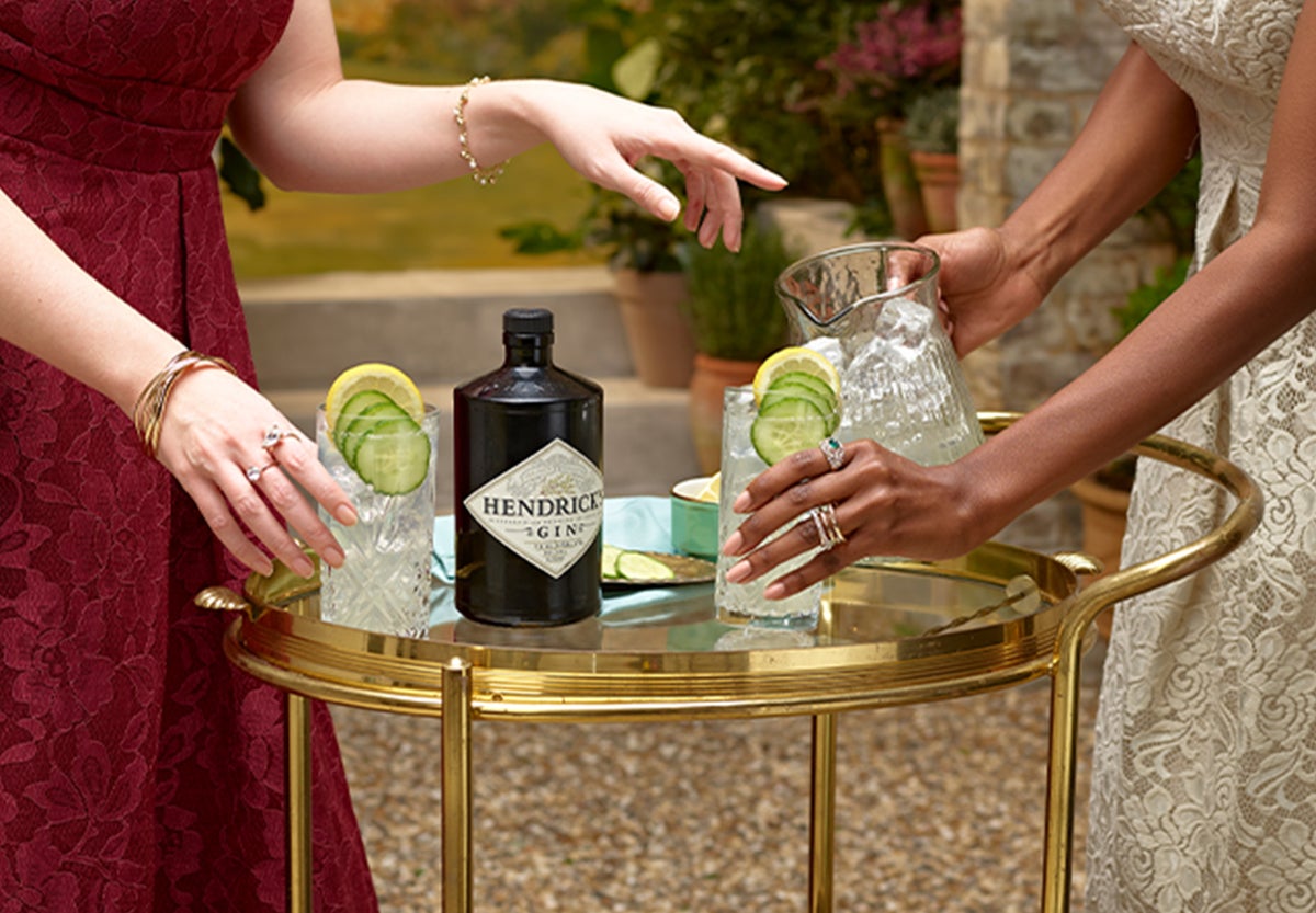 2 women with a drinks trolley with glasses and a bottle of Hendricks Gin