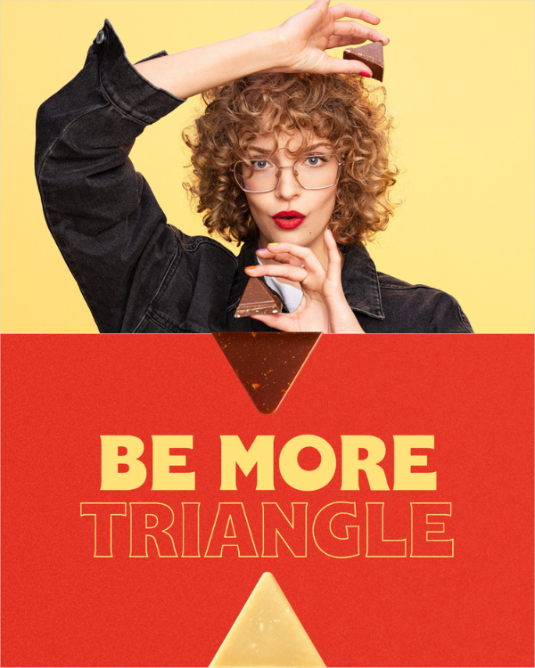 Woman with curly hair and glasses holding two pieces of Toblerone on a Yellow background.