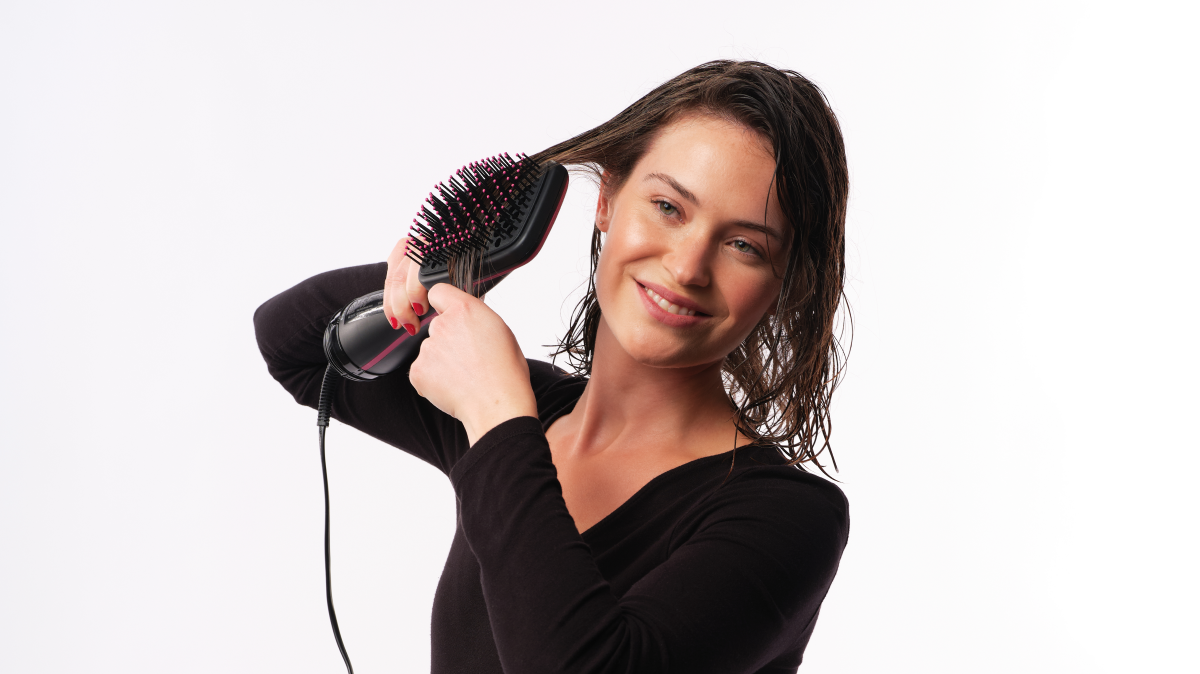 Women using the revlon one step hair styler and dryer to straighten her hair