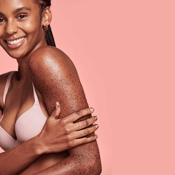 1 woman smiling with scrub on her body. Other woman looking dreamy with cream on her face.