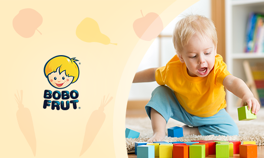 Dziecko bawiące się kolorowymi klockami, obok logo Bobo Frut.