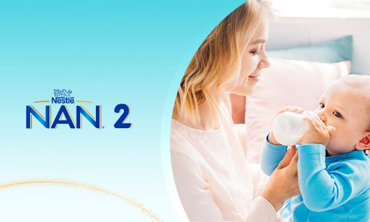 Baner ze zdjęciem młodej mamy, karmiącej swoje dziecko mlekiem Nan2, z butelki dla dzieci, obok logo Nestle Nan2.