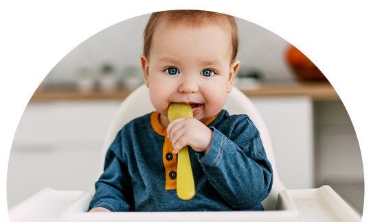 Dziecko, siedzące na wysokim krześle i jedzące zdrową żywność dla dzieci, z żółtej łyżki.