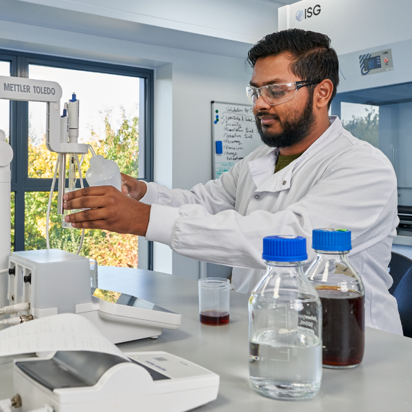 Male scientist working in a lab pouring liquid in a container.