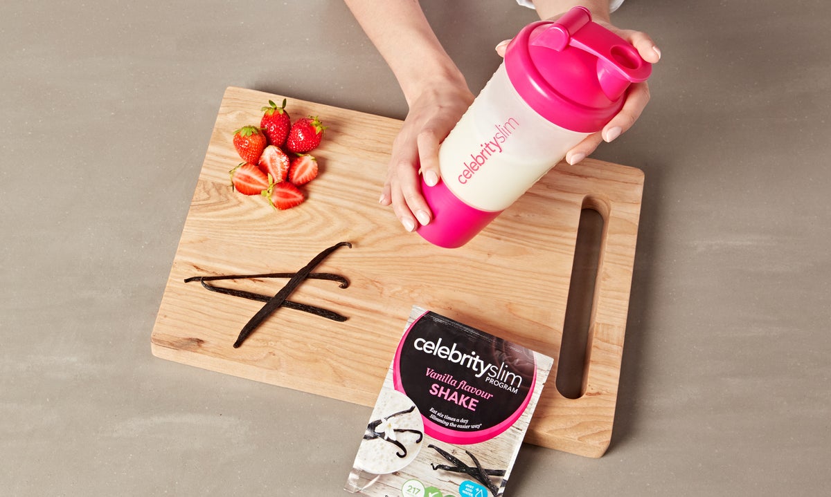 Celebrity Slim Vanilla Flavour Shake in a shaker with strawberries and vanilla pods on a chopping board