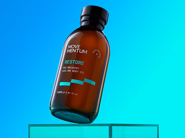 movementum restore pro recovery cooling body oil, set against a blue background resting at an angle on a table