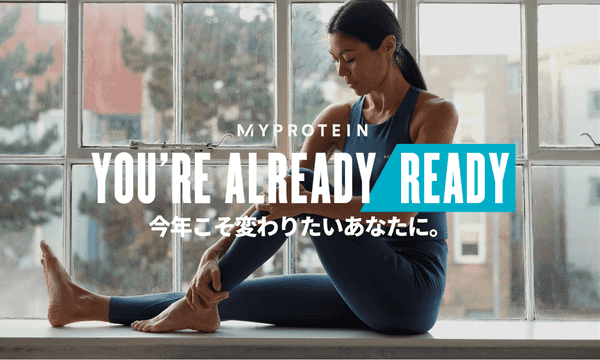 A woman wearing MP gym clothing sat on a window ledge stretching with the text 'You're Already Ready - MYPROTEIN' overlaying the image.