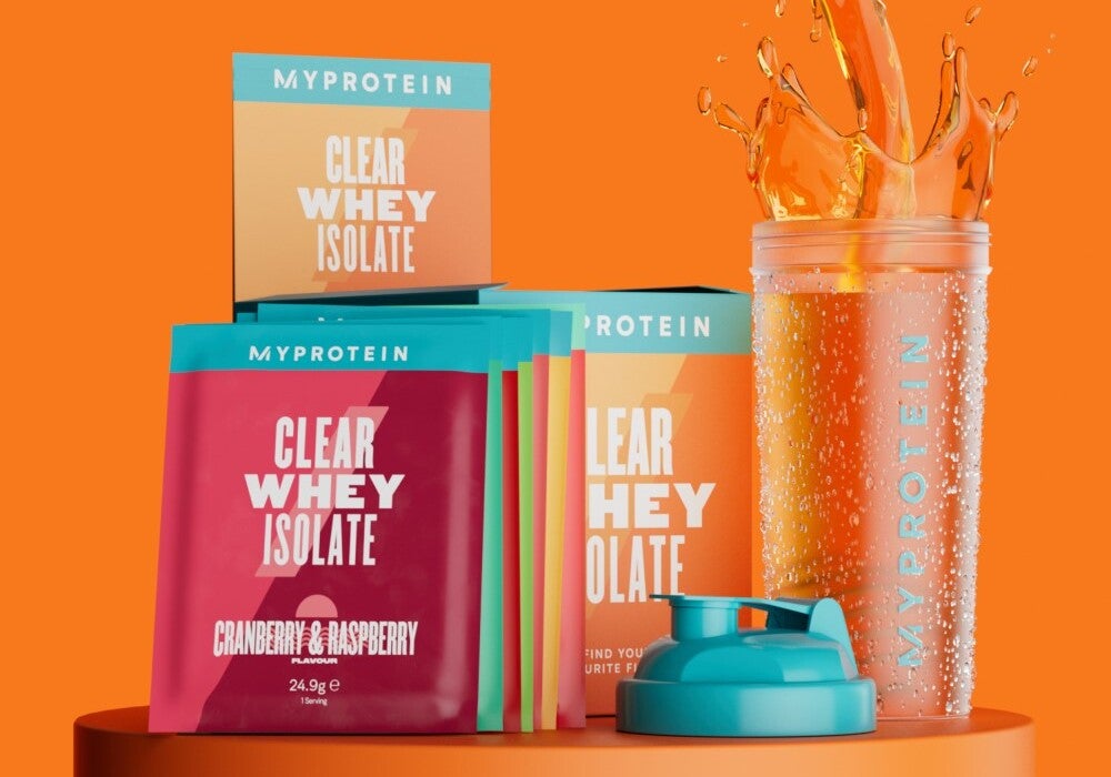 De clear whey sample pack op een podium met verschillende smaken, waaronder cranberry & framboos en sinaasappel mango, naast een shaker met het Myprotein-logo.