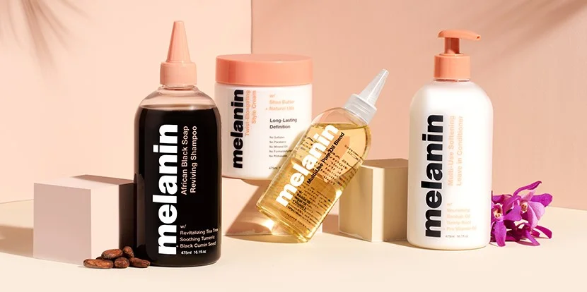 Four hair products with minimalistic packaging. From left to right: a shampoo, curl cream, hair oil and leave-in conditioner