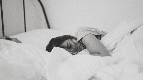 Woman sleeping in towel on dark grey bedding