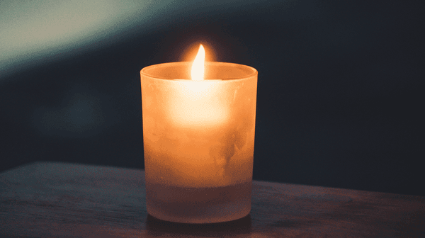 Lit candle in front of dark background