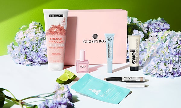 Pink GLOSSYBOX surrounded by blue flowers and 6 beauty products