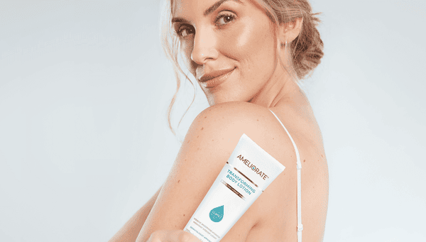 Woman sat in bath with Ameliorate nourishing body wash and Ameliorate smoothing body exfoliant on bath rack
