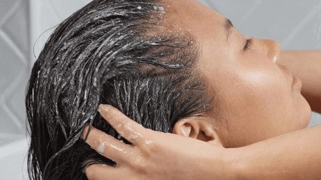 woman scrubbing her scalp with a christophe robin scalp scrub