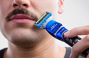 Man trimming moustache with Gillette Styler.