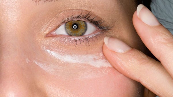 Woman applying cream to get rid of puffy eyes