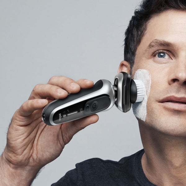 man using Series 7 with cleaning brush attachment on his face, with cleansing cream on his cheek