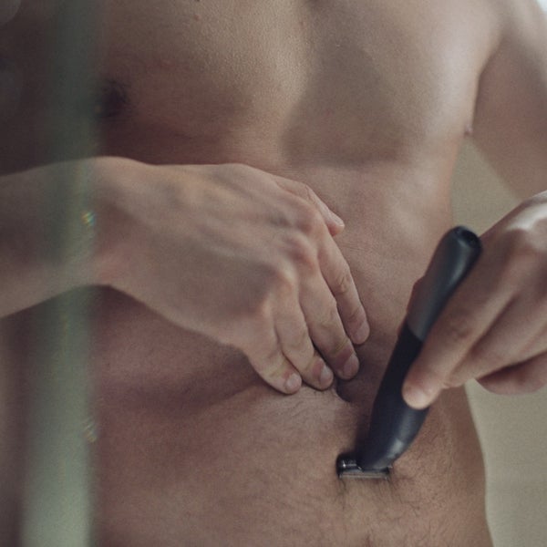 close up of mans torso in the shower shaving the lower part of his stomach with Series X
