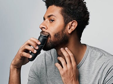 Beard Trimmers - Braun - man's head and shoulders showing as he uses beard trimmer 7 to shape his beard's mustache