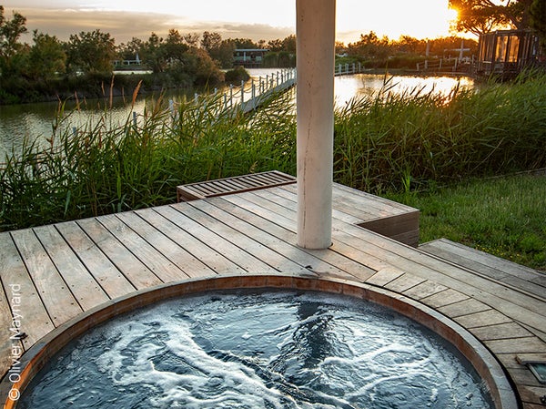 Le Mas de la Fouque… là où la nature est reine, où le temps s’arrête, où la douceur vous enivre et où le luxe est finalement un plaisir simple. Bienvenue dans un hôtel d’exception au cœur de la Camargue, entre lagunes et terres sauvages. Ici et là, tout n’est que calme et volupté. Les chambres, suites et roulottes sont équipées pour offrir un confort idéal et une nuit des plus paisible aux convives. Il n’y a qu’à choisir celle qui vous fait le plus rêver… Le restaurant gastronomique « La Table de Marius » transporte vos papilles en terres camarguaises. Une sélection des meilleurs produits locaux est proposée : du tant convoité taureau AOP Camargue au sel camarguais, la carte respire les saveurs du sud. Le Mas de la Fouque vous invite à vivre une escapade douceur dans son Spa Nuxe. Abandonnez-vous entre des mains expertes et profitez de toute la sérénité que ce lieu au charme exceptionnel a à offrir : massages, gommages, soins, l’espace bien-être propose également une piscine intérieure chauffée, une cascade de glace ainsi qu’un bain hydro-massant. Envie de « buller » sous le soleil camarguais ? L’établissement est également équipé d’un bain hydro-massant extérieur, à l’abri des regards et sur le point culminant de l’hôtel, offrant une vue somptueuse. Du restaurant au spa, en passant par les hébergements et les lieux de vie commune, le Mas de la Fouque vous invite à vivre une expérience hors du commun. A deux pas du parc ornithologique, à seulement quelques minutes des manades et quelques encablures des plages sauvages, soyez libre de composer votre séjour à l’infini. Pause nature, escapade romantique, séjour bien-être ou sportif, instant gourmand ou relaxant, le temps d’une matinée, d’une journée ou plus encore… l’authenticité de la Camargue se marie avec toutes vos envies. Observez. Respirez. Écoutez ce rythme lent et enivrant. Au Mas de la Fouque, vivez le sud autrement.