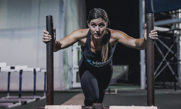 Klean Athlete woman pushing weights in the gym