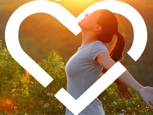 Individual smiling and posing with a sunset backdrop, surrounded by heart logo