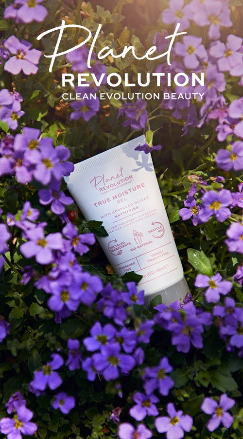 Planet Revolution. Skincare bottle lay among small lilac flowers.