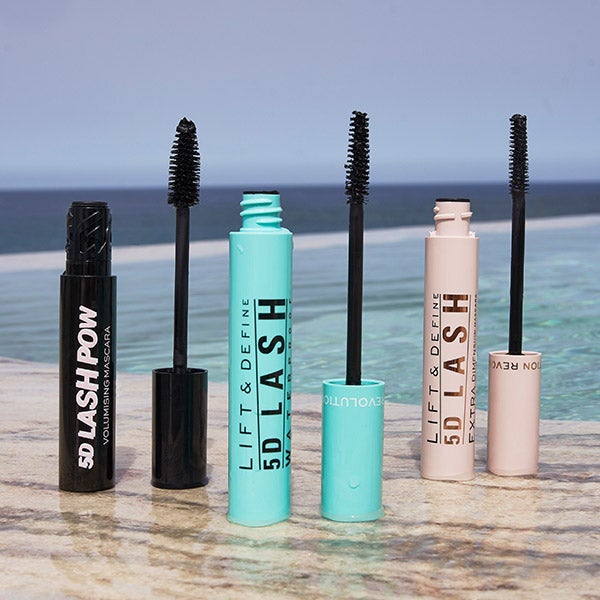 Three mascaras stood up, open with their brushes next to them.
