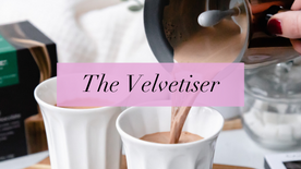 the velvetiser in black text, set against a pink background, with someone pouring hot chocolate into a cup
