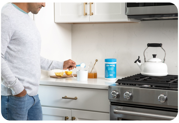 Vital Proteins collagen peptides on kitchen top with a women in the background drinking coffee