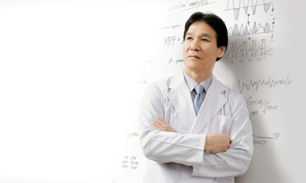 Doctor in white uniform with equations on whiteboard behind