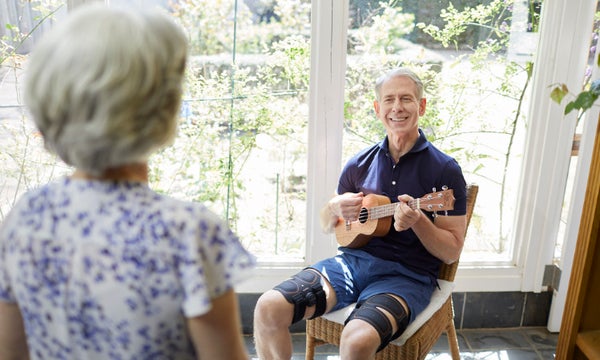 Man smiling playing the guitar whilst using sixpad leg belts