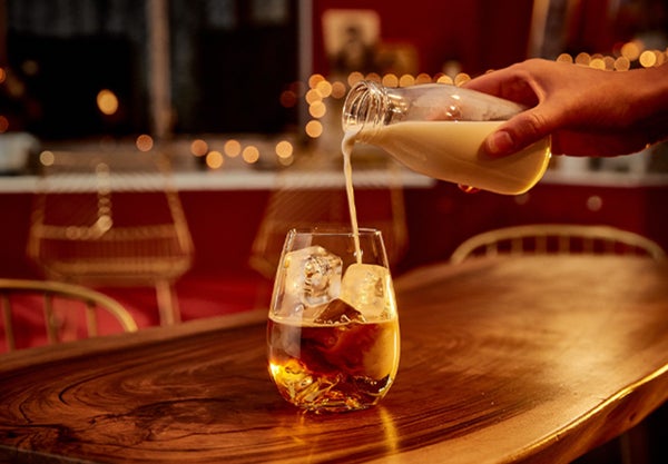 A drink being poured into a glass of whiskey