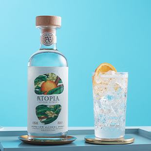 Bottle of Atopia with drink next to it